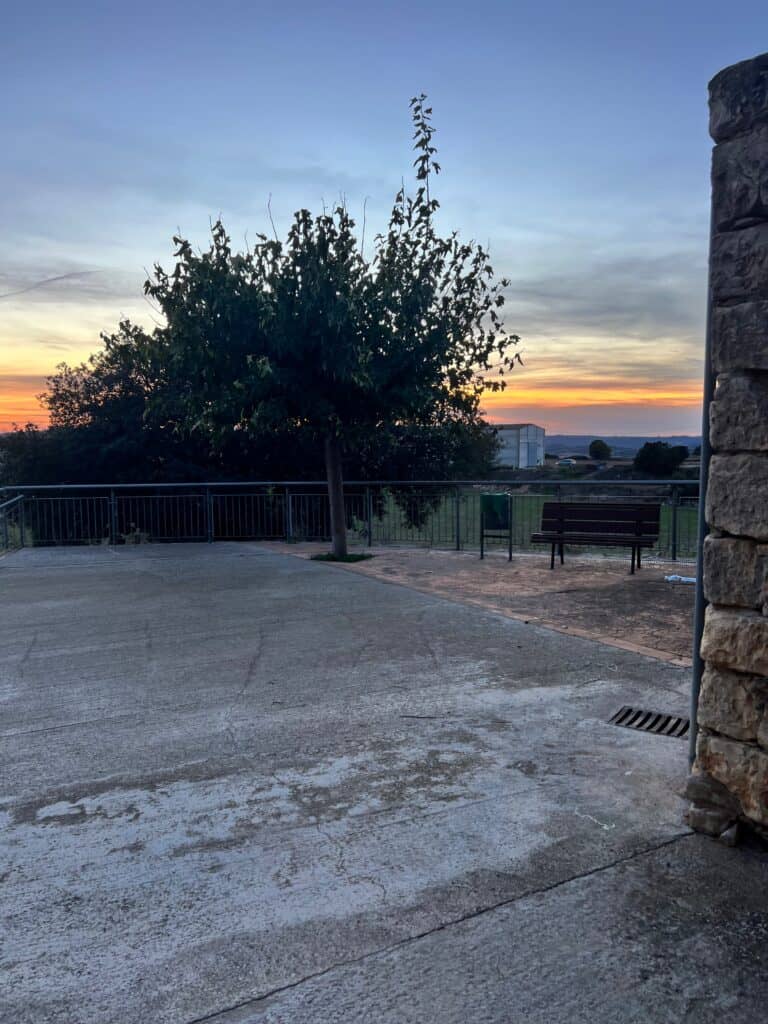 Sunset view from Casa Pardal's front patio, with a bench overlooking the countryside and evening colors in the sky.